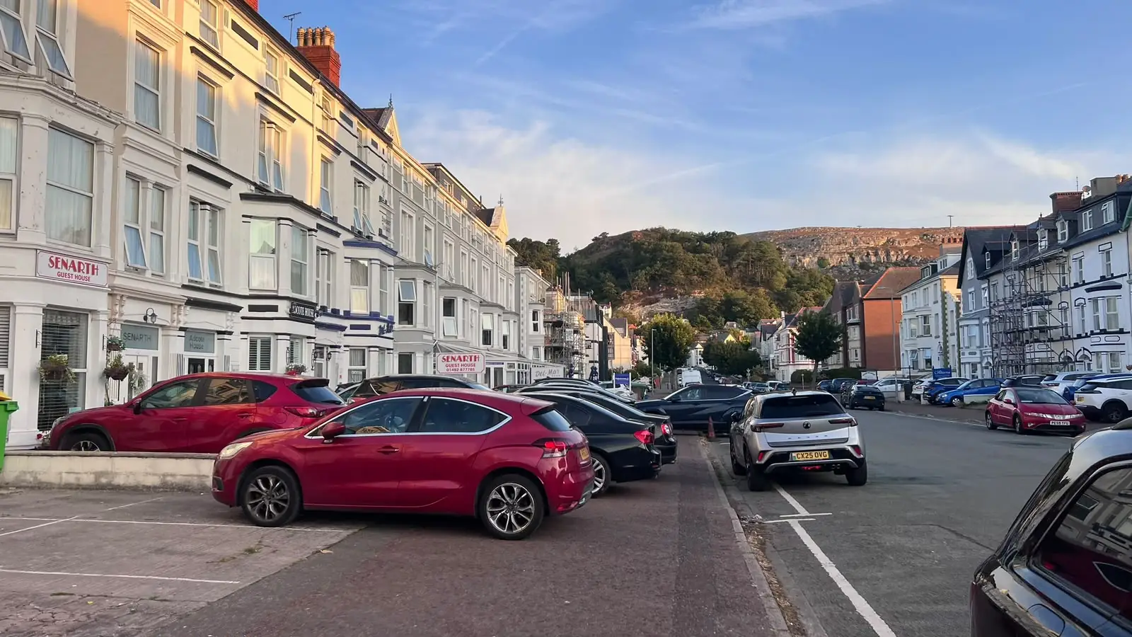 The front of GOAT House on a Llandudno terrace, with the Great Orme headland rising behind (photographed before the rebrand, so the sign still shows the previous name)