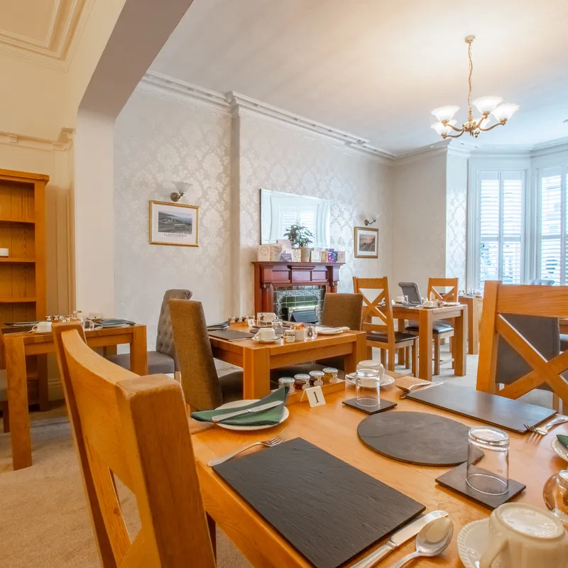 The breakfast room, with oak tables laid for breakfast and a bay window with shutters