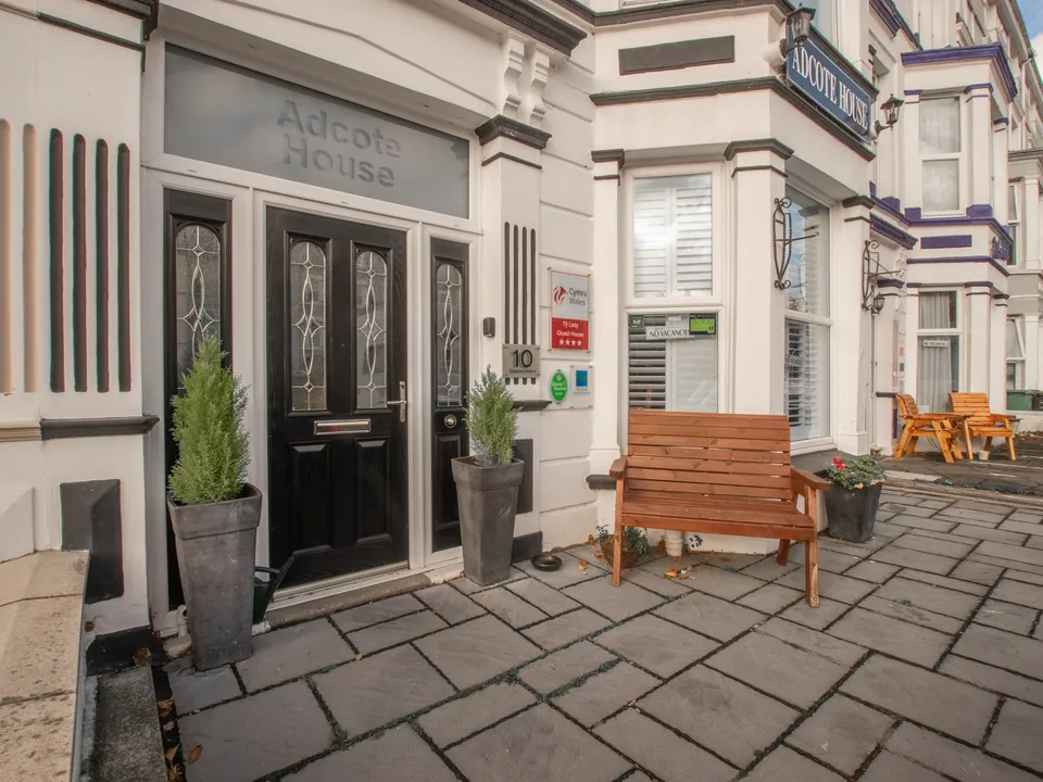 The front door and patio, with a wooden bench and potted plants