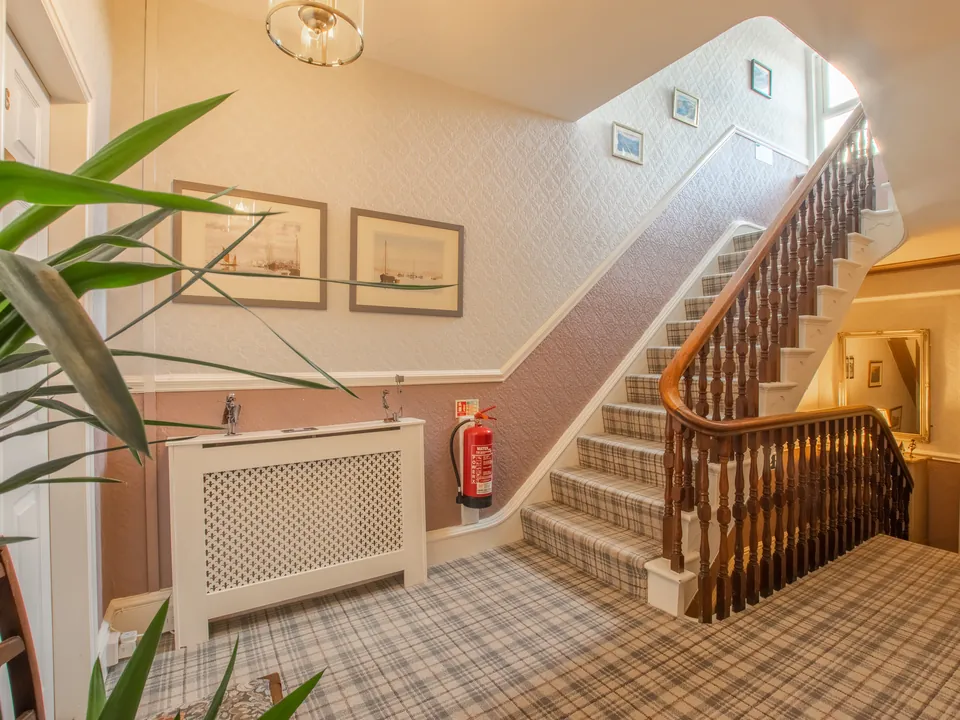 The hall and staircase, with pictures of the coast on the walls