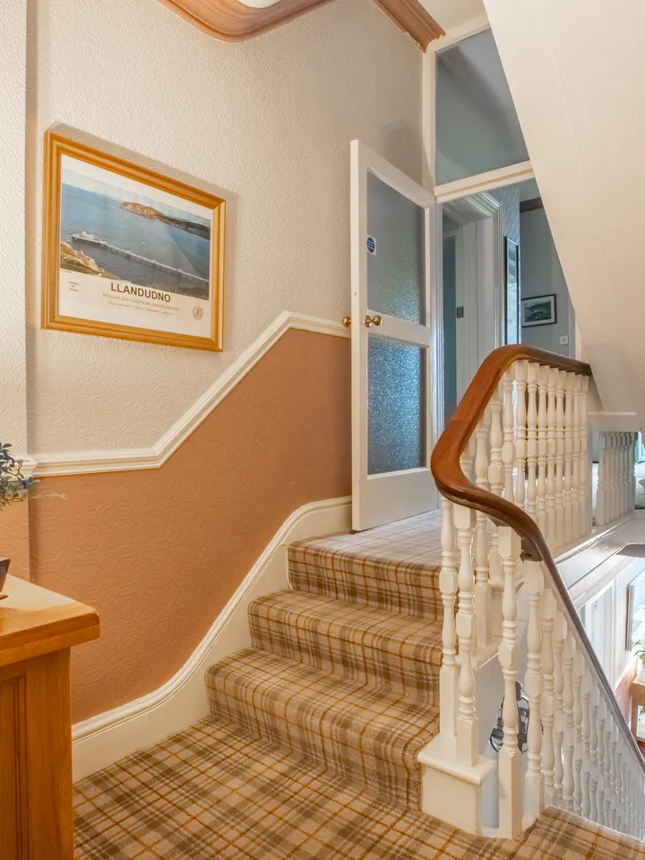 The staircase, with a tartan carpet and a wooden banister