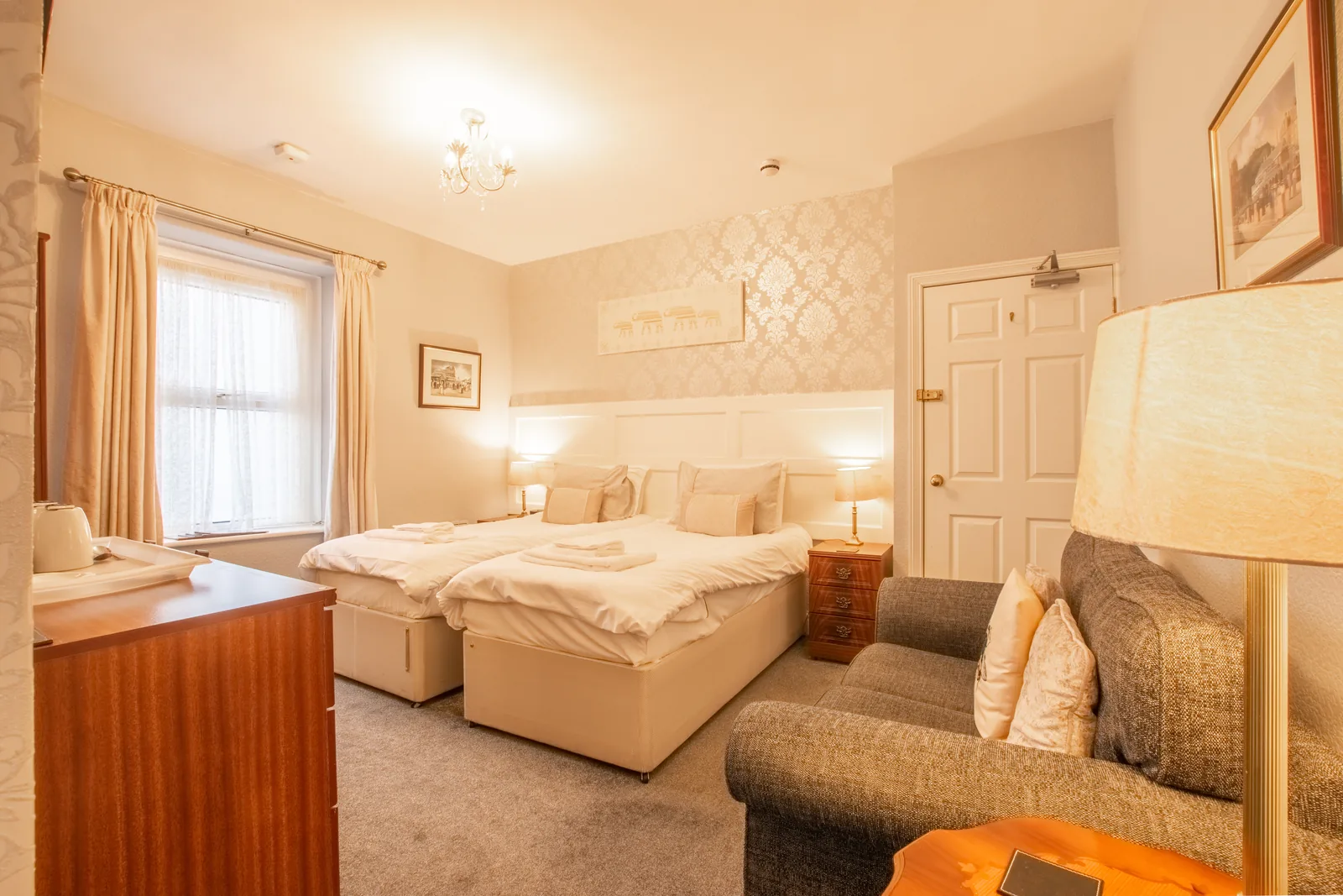 Beaumaris, Room 1: the twin beds, a sofa and a reading lamp, with the window behind