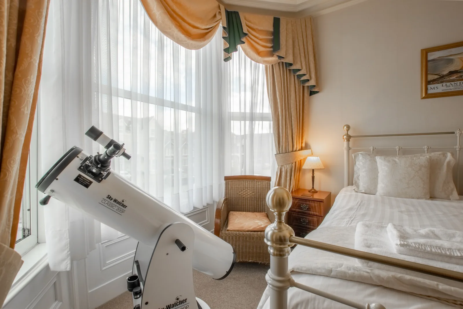 Adcote Suite, Room 3: the telescope at the bay window, beside the bed and a wicker armchair