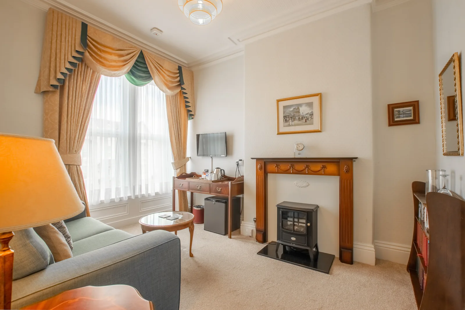 Adcote Suite, Room 3: the sitting room, with a sofa, an electric fire in a wooden surround, a writing desk and a TV
