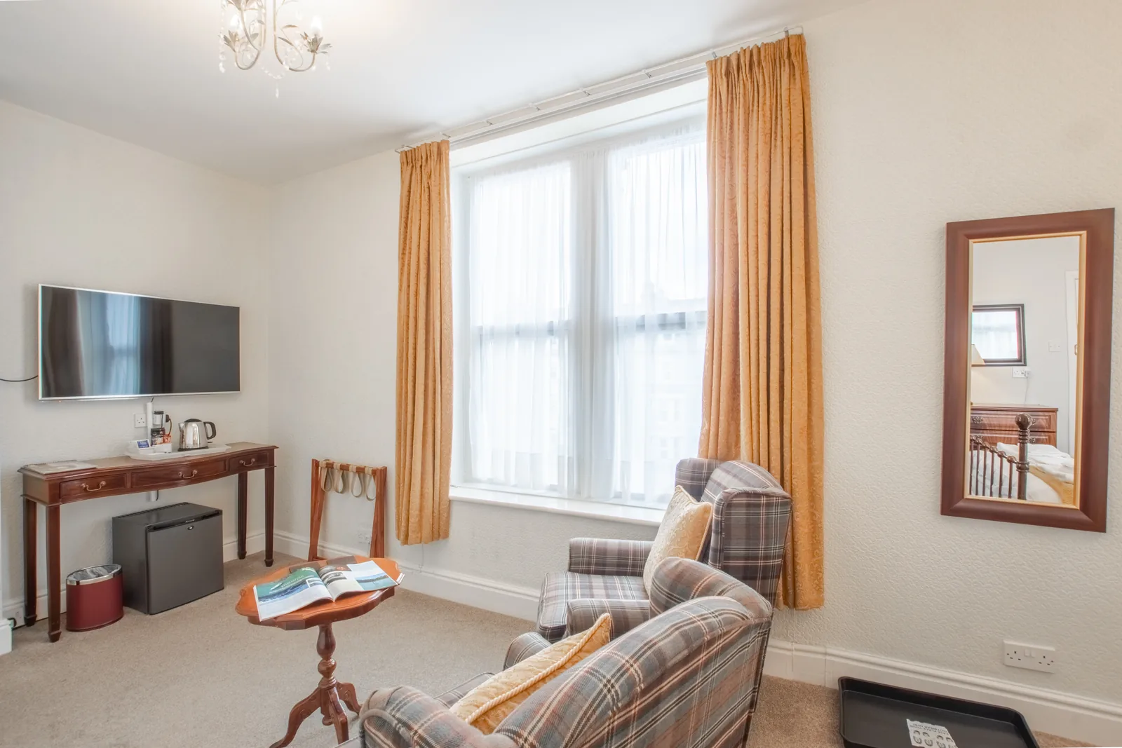 Conwy Studio, Room 6: the tartan armchairs, a writing table, a fridge and a wall-mounted TV